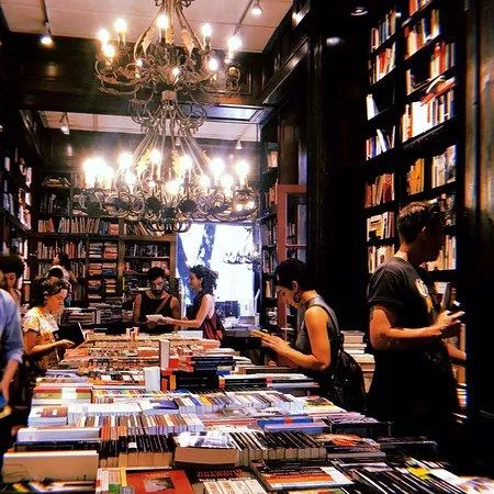 Livraria e editora Eterna Cadencia Ambiente interno da livraria Eterna Cadencia com estantes de madeira.