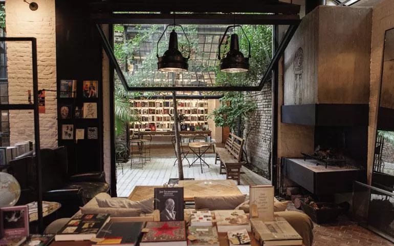 O pátio charmoso da Falena Libros Área externa da livraria Falena Libros, com pátio e plantas.