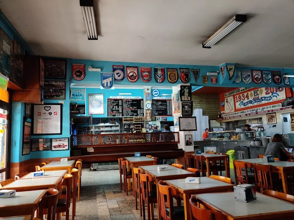 A tradicional pizzaria El Cuartito Interior da pizzaria El Cuartito, com decoração temática de futebol.